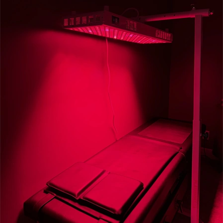 Red light therapy panel mounted above a padded therapy table
